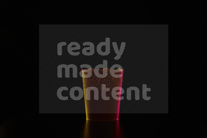 A plant pot with colored rim light against black background