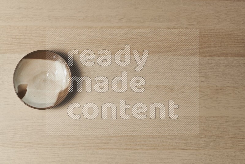 صحن فخاري متعدد الألوان على خلفية خشبية فاتحة