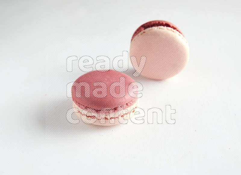 45º Shot of two Pink Litchi Raspberry macarons on white background