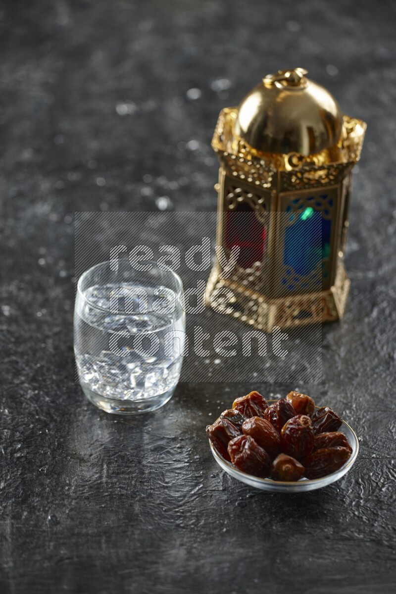 A golden lantern with different drinks, dates, nuts, prayer beads and quran on textured black background