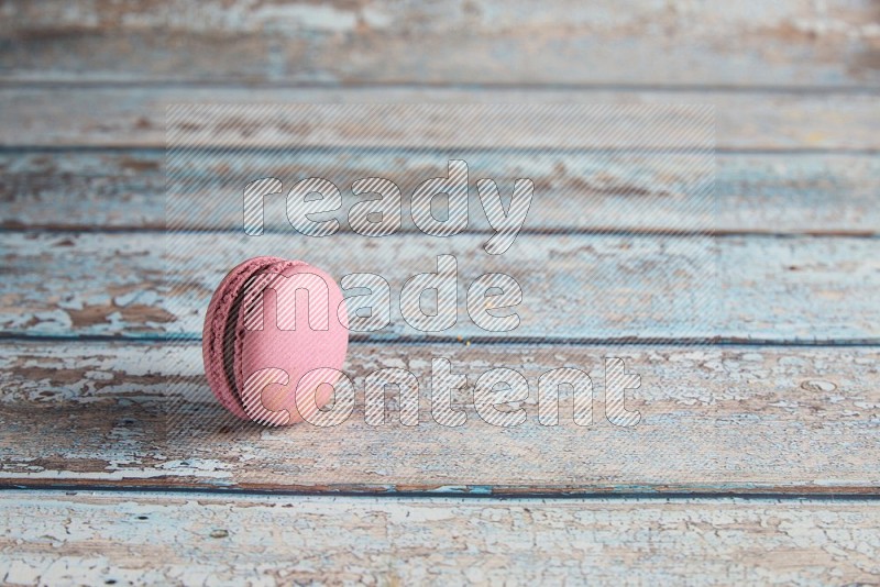 45º Shot of Purple Strawberry macaron on light blue wooden background