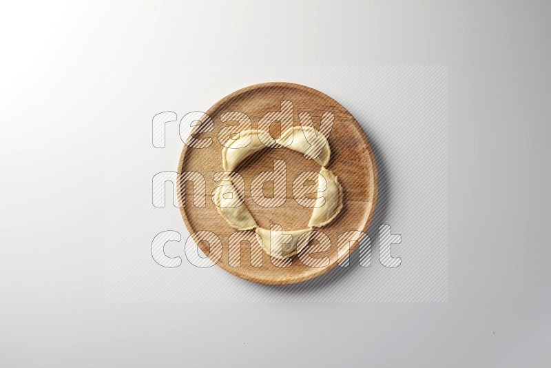 Five Sambosas on a wooden round plate on a white background