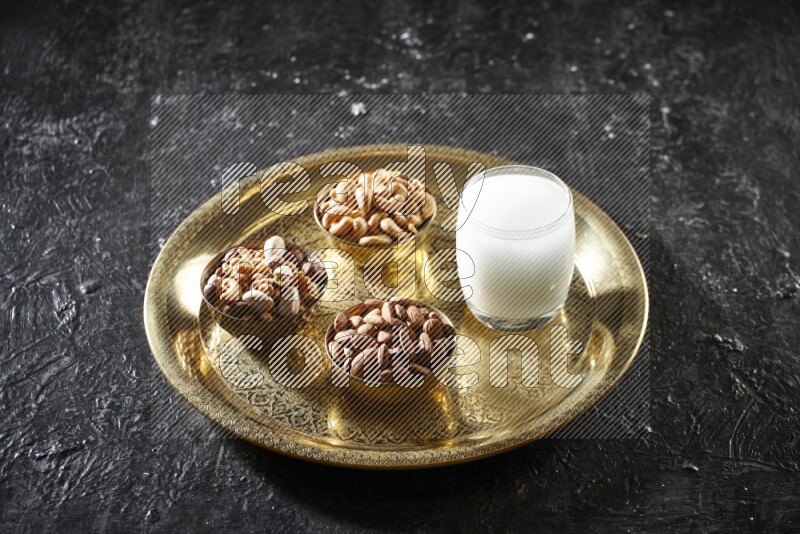 مكسرات في أطباق معدنية مع السوبيا على صينية علي خلفية سوداء