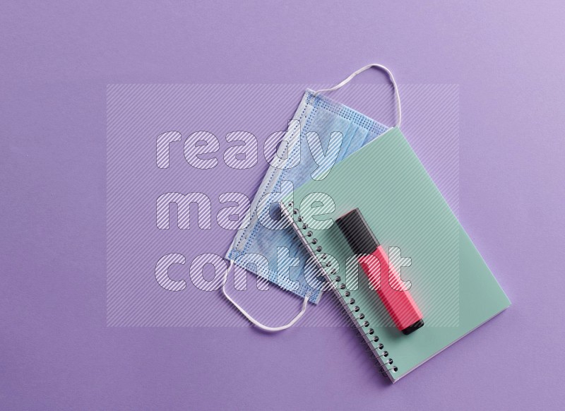 A blue note book with school supplies on purple background (Back to school)