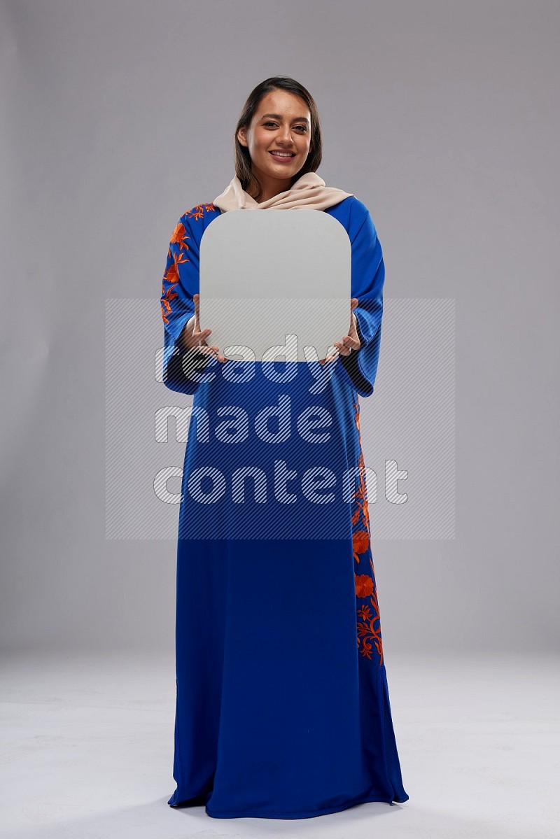 A Saudi woman standing wearing Jalabeya holding a social media sign