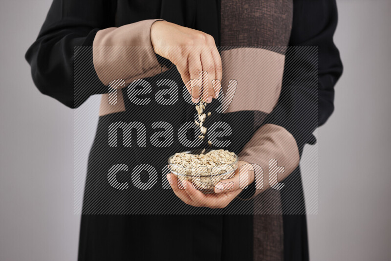 Woman in abaya holding different kinds of legumes in different positions