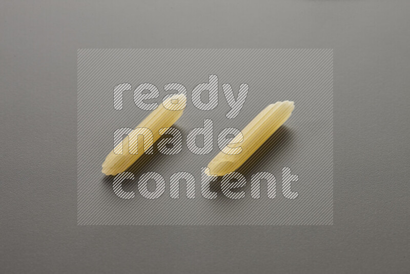 Mini penne pasta on grey background
