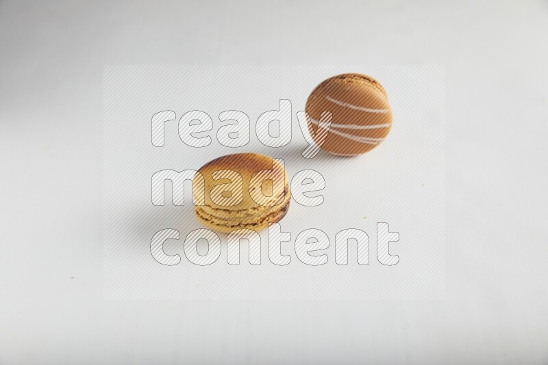 45º Shot of of two assorted Brown Irish Cream, and Yellow Crème Brulée macarons on white background