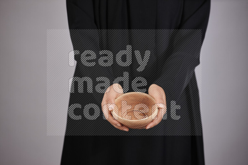 A woman in black abaya holding different wooden essentials in different positions