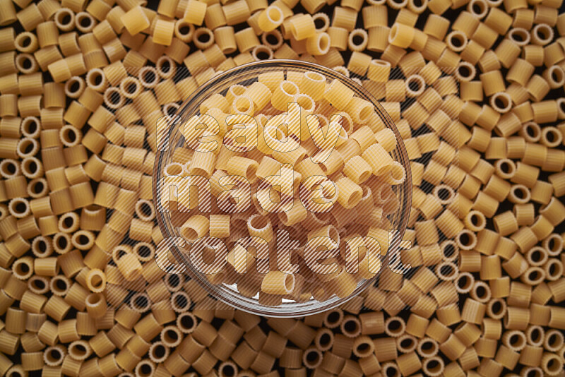 Big rings pasta in a glass bowl on black background