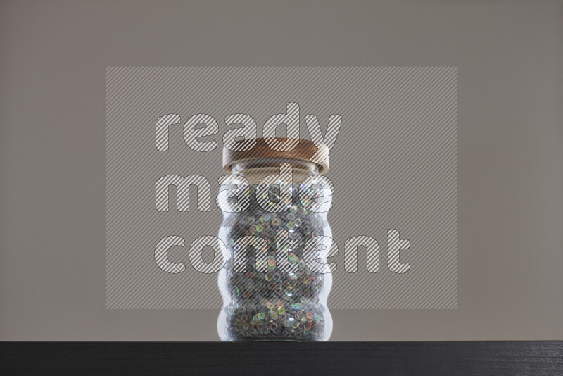 Sequins in a glass jar on black background