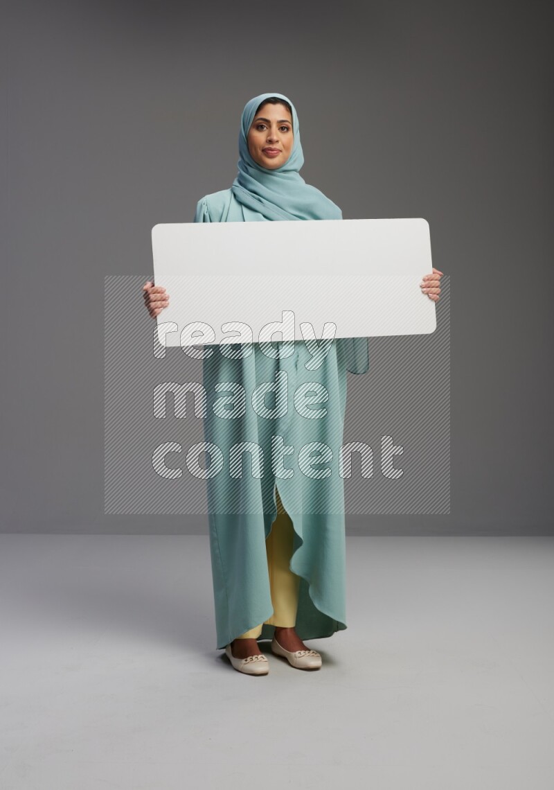 Saudi Woman wearing Abaya standing holding board on Gray background