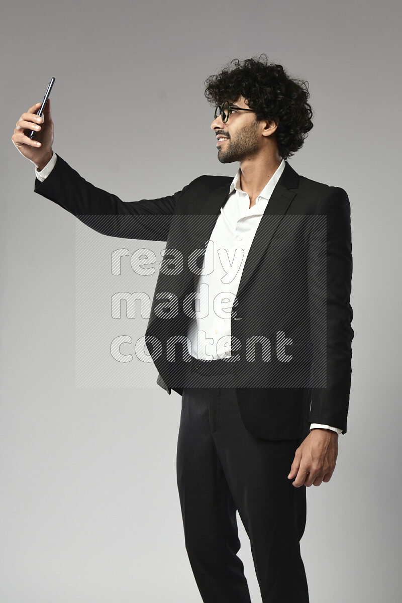 A man wearing formal standing and taking a selfie on white background