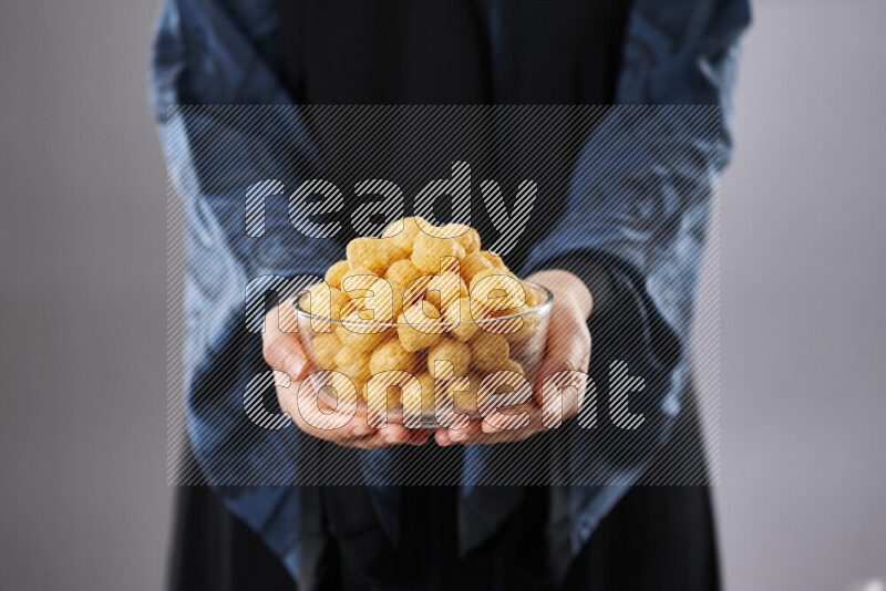 Woman in abaya holding different kinds of snacks in different positions