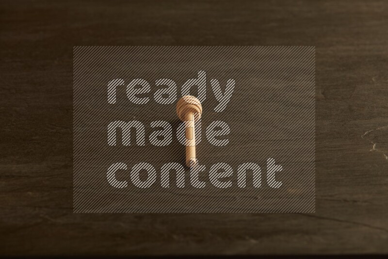 Wooden honey dipper on black slate background