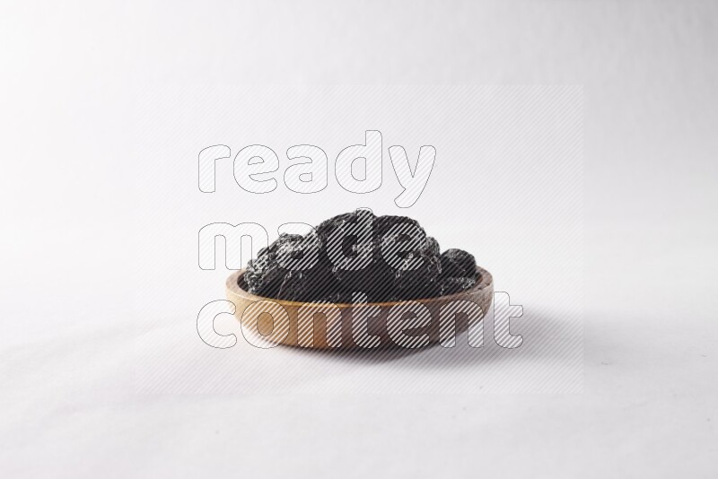Dried plums in a wooden bowl on white background