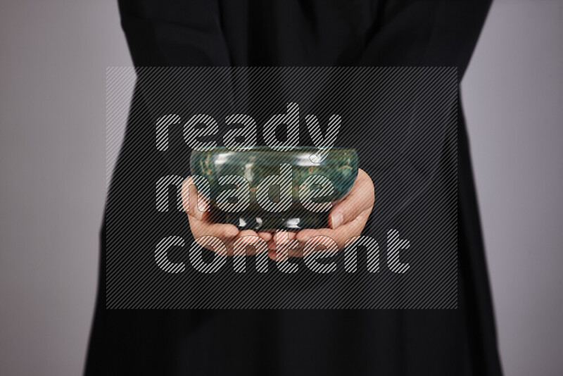 A woman in black abaya holding different pottery essentials in different positions