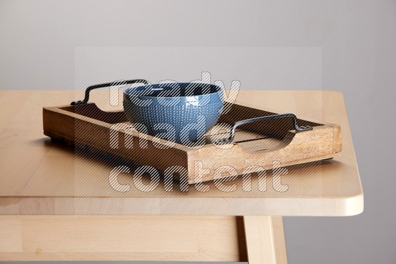 blue bowl on a light colored rectangular wooden tray with handles