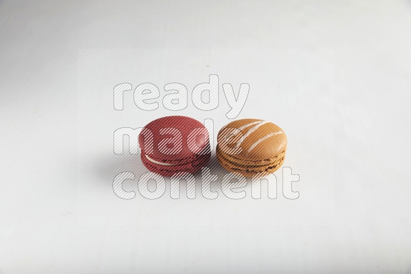 45º Shot of of two assorted Brown Irish Cream, and Red Velvet macarons on white background