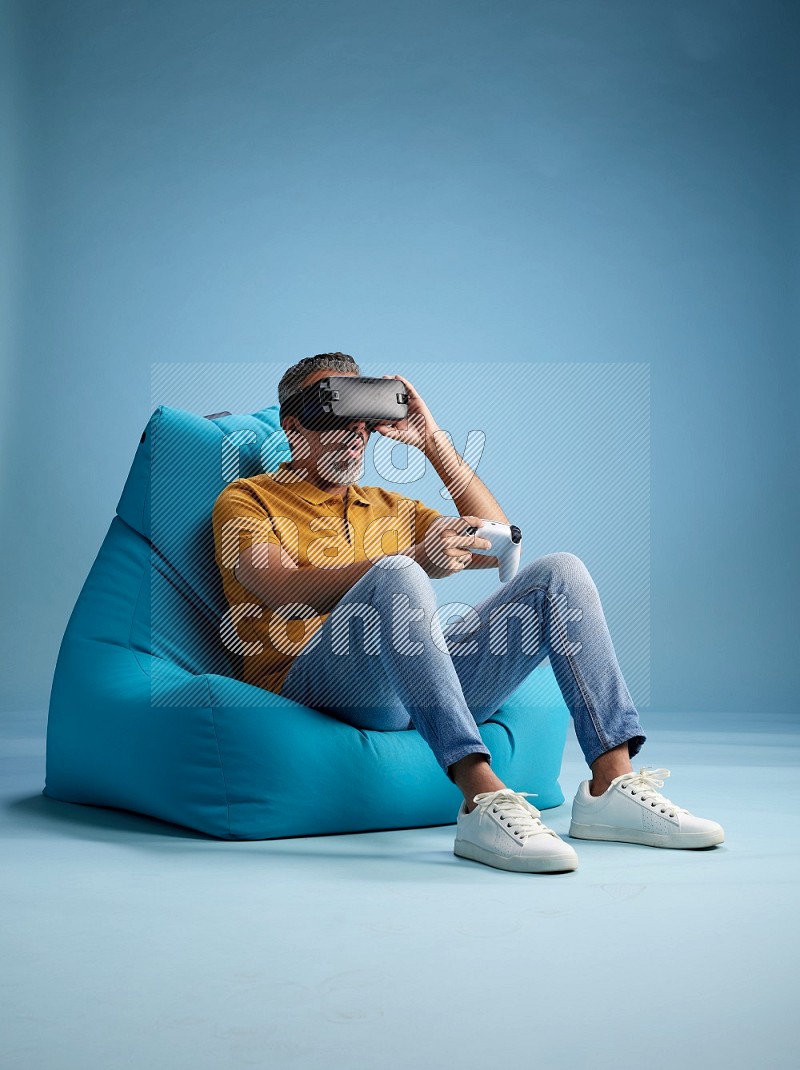 A man sitting on a blue beanbag and gaming with VR