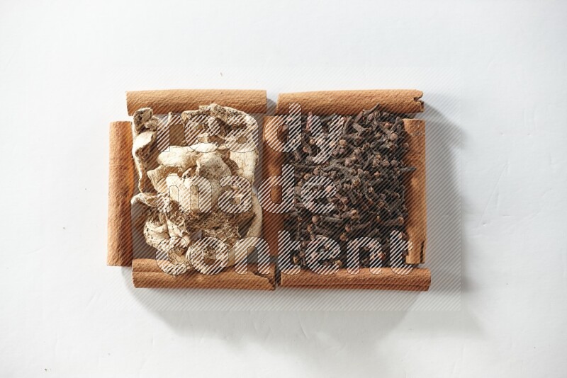 2 squares of cinnamon sticks full of cloves and dried ginger on white flooring