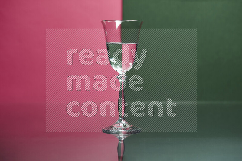 The image features a clear glassware filled with water, set against pink and dark green background