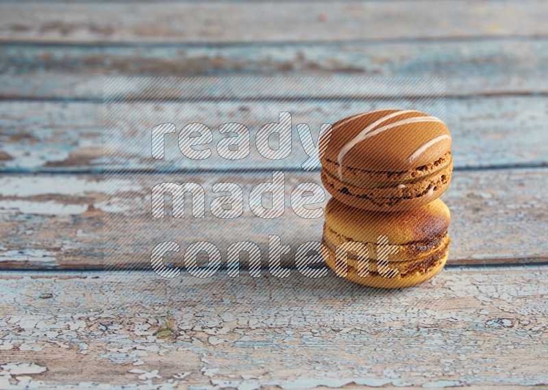 45º Shot of of two assorted Brown Irish Cream, and Yellow Crème Brulée macarons on light blue background