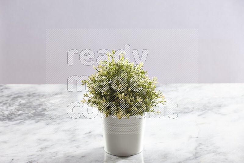 Artificial plant in white pot on grey marble background