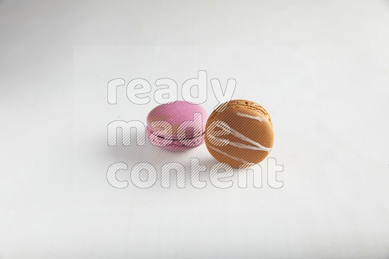 45º Shot of of two assorted Brown Irish Cream, and Purple Strawberry macarons on white background