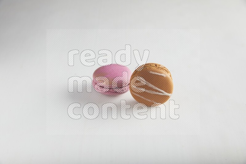 45º Shot of of two assorted Brown Irish Cream, and Purple Strawberry macarons on white background