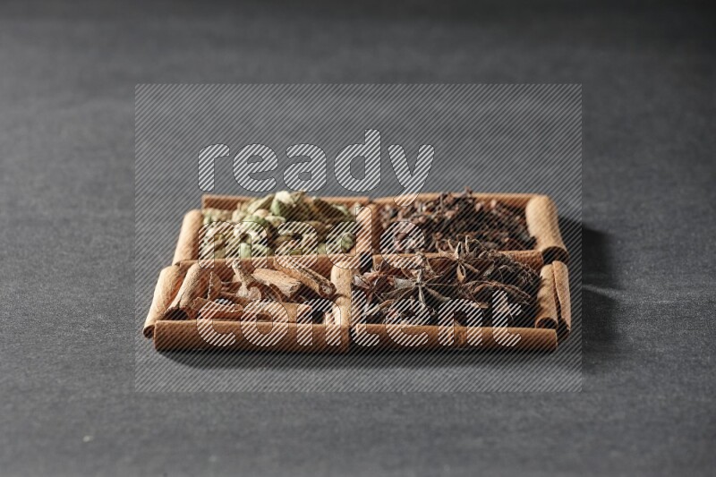 4 squares of cinnamon sticks full of cinnamon, cardamom, cloves and star anise on black flooring