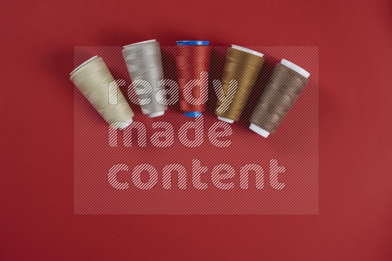 A brown and red collection of sewing and tailoring tools arranged on a red background