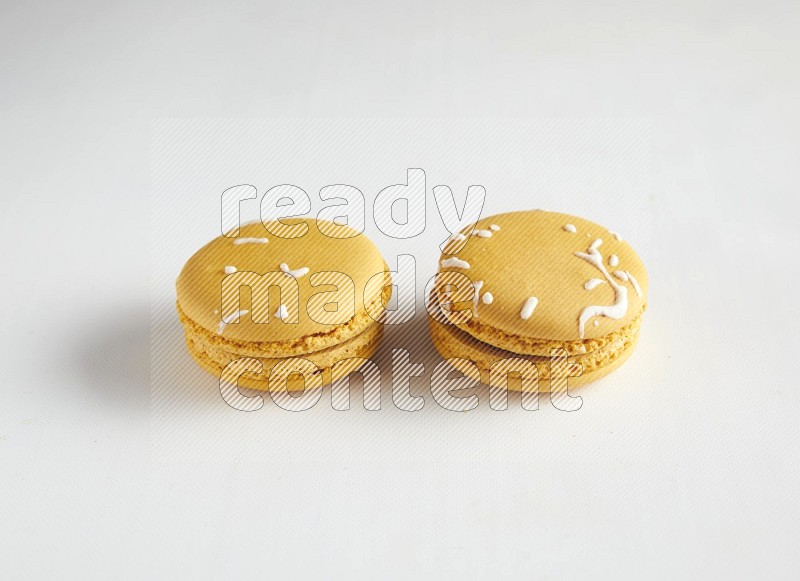 45º Shot of two Yellow Piña Colada macarons on white background