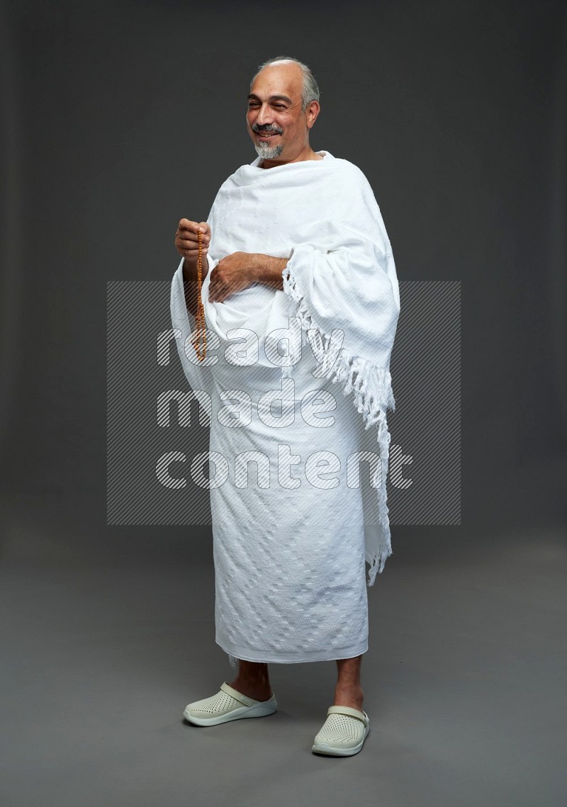 A man wearing Ehram Standing holding rosary on gray background