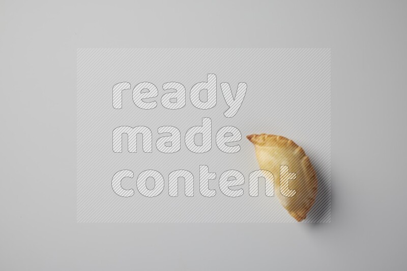 One fried sambosa from a top angle on a white background
