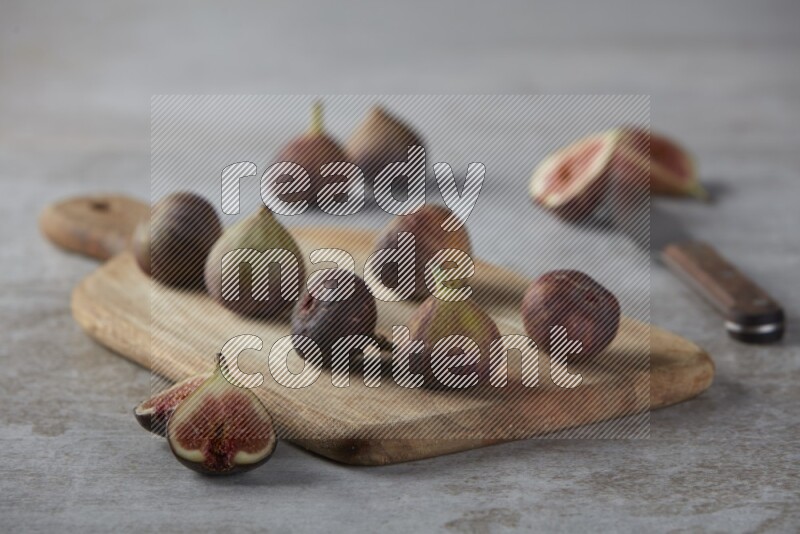 Fresh Figs on a wooden board on a textured grey background