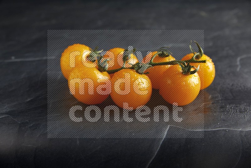 Yellow cherry tomato vein on a textured black slate background 45 degree