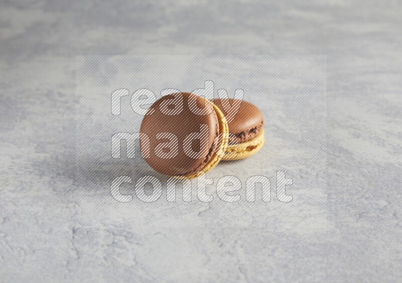 45º Shot of two Yellow and Brown Chai Latte macarons r on white  marble background
