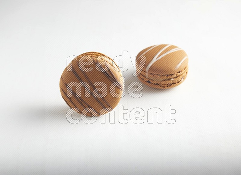 45º Shot of of two assorted Brown Irish Cream, and light brown  Almond Cream macarons on white background