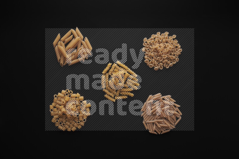 Different pasta types in bunches on black background