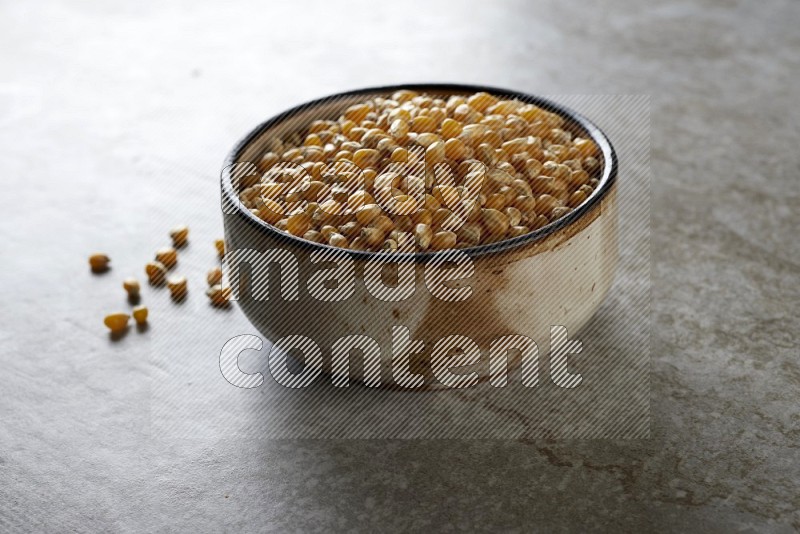 corn kernel in multi-colored pottery bowl on a grey textured countertop