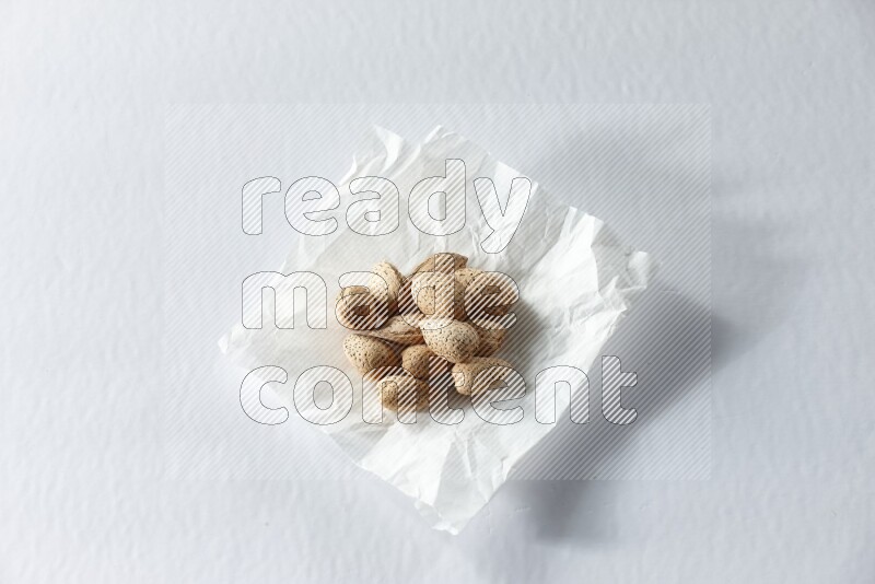 Almonds on a crumpled piece of paper on a white background in different angles
