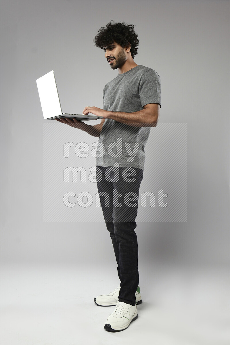 A man wearing casual standing and working on a laptop on white background