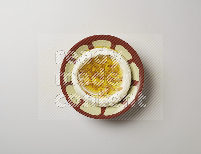 Lebnah garnished with pine nuts in a traditional plate on a white background