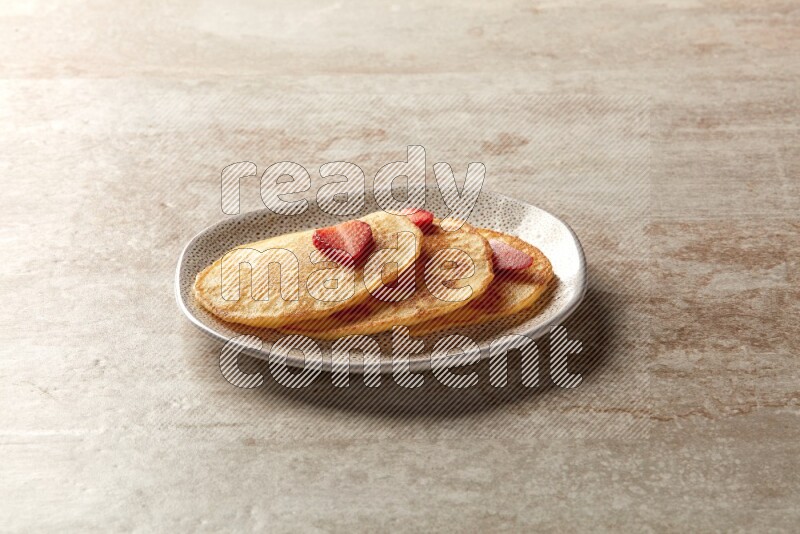 Three stacked strawberry pancakes in an irregular plate on beige background