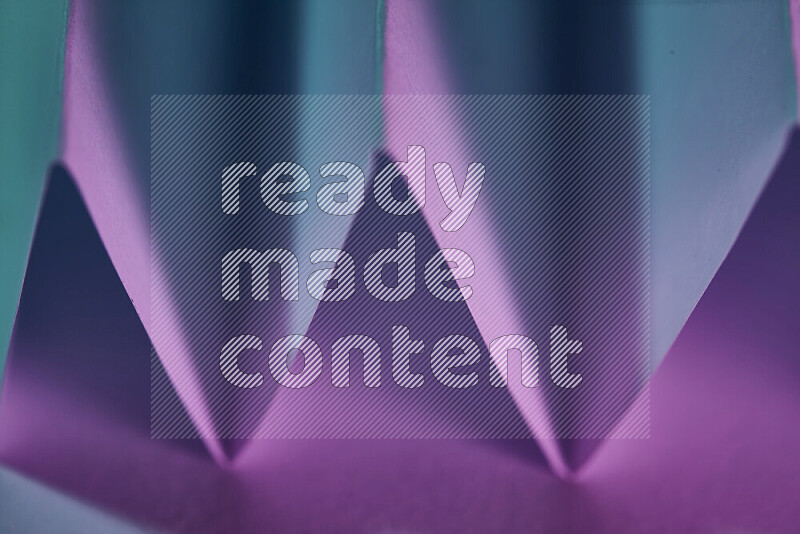 A close-up abstract image showing sharp geometric paper folds in blue and purple gradients