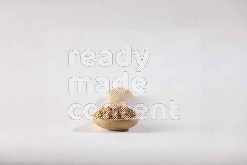 ملعقة خشبية ممتلئة ببذور الخردل علي خلفية بيضاء