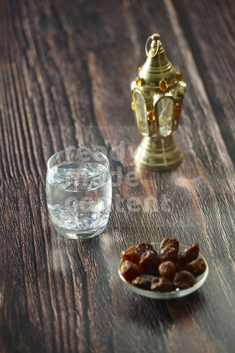 A golden lantern with different drinks, dates, nuts, prayer beads and quran on brown wooden background