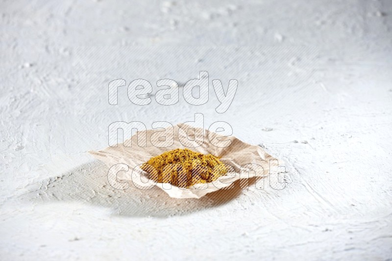 Turmeric powder in a crumpled piece of paper on textured white flooring