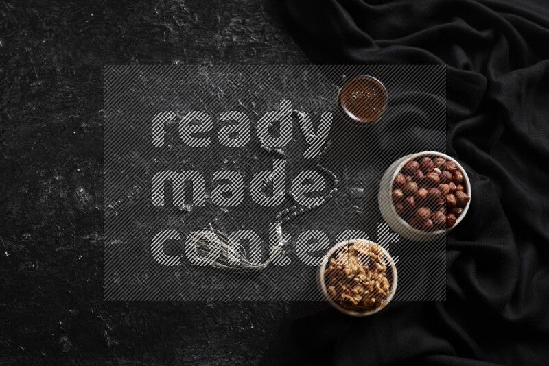 مكسرات في أطباق فخارية مع القهوة علي خلفية سوداء خشبية